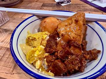 Rice bowl with glazed meat, egg or dumpling, vegetables, and chopsticks at Uncle Soon Plus Kitchen House