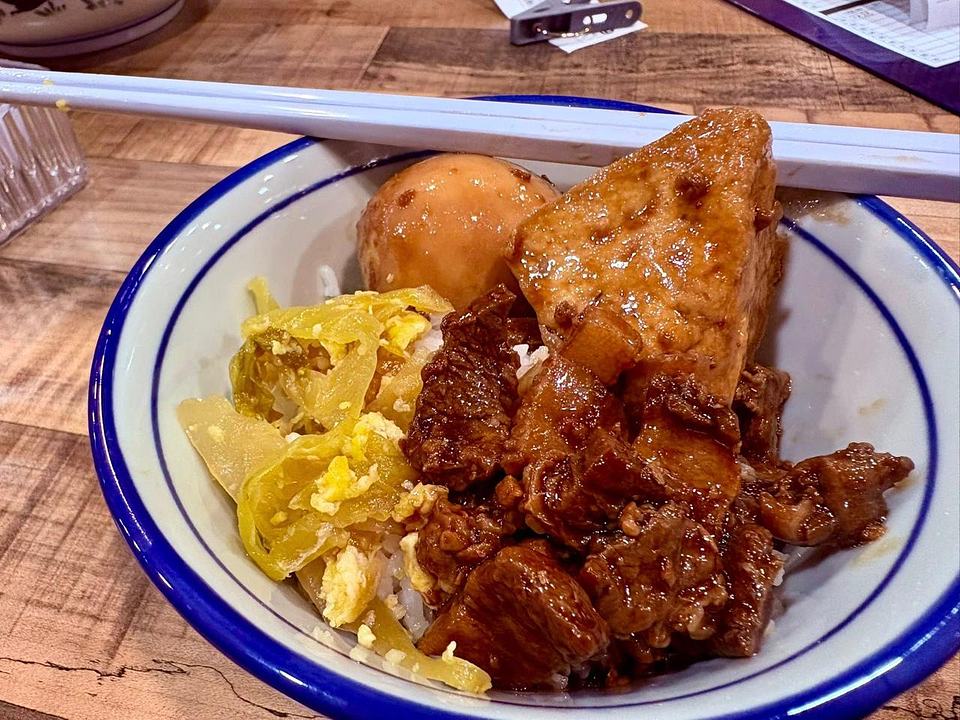 Rice bowl with glazed meat, egg or dumpling, vegetables, and chopsticks at Uncle Soon Plus Kitchen House