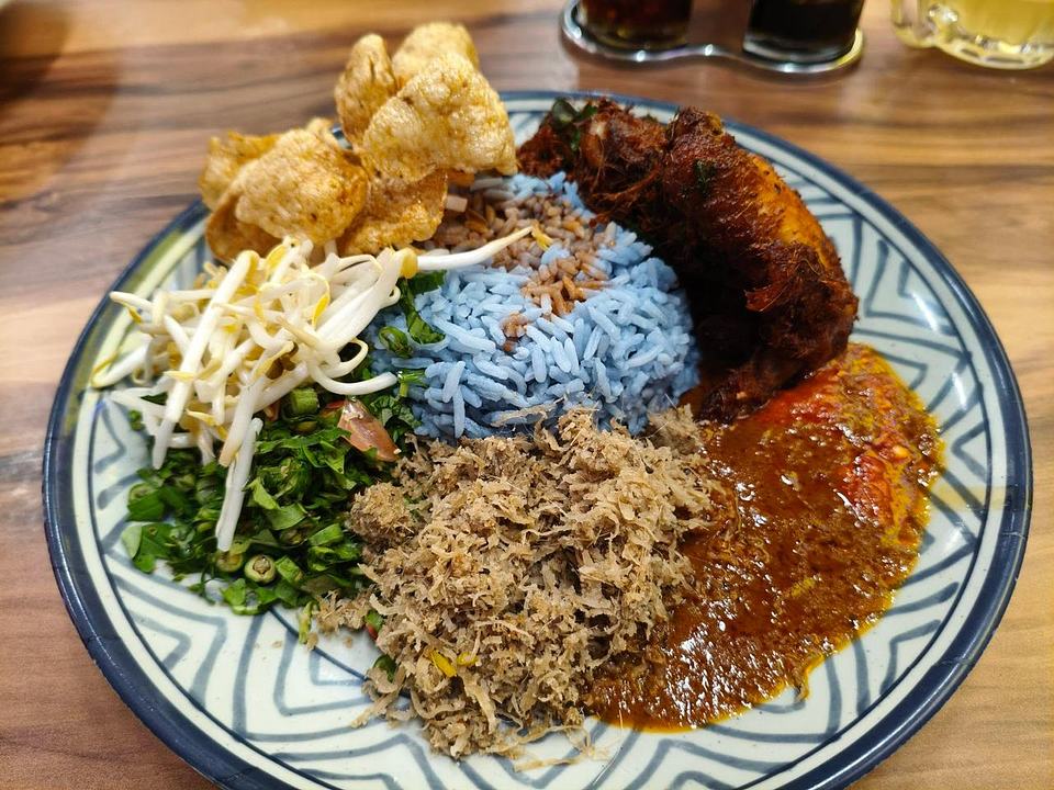 Nasi kerabu with blue rice, dark meat, red sauce, vegetables, and crispy fritters at Mace Mache