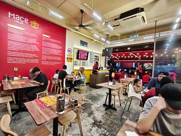 Interior of Mace Mache restaurant with red and yellow walls, wooden tables, and counter service