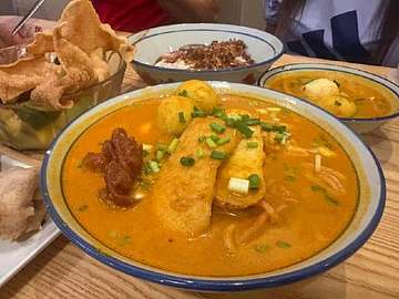Rich curry with crispy fried fish fillets, dumplings, and flatbread at Bibi's Popiah