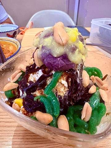 Layered jelly dessert with green and purple layers, topped with sauce and peanuts at Bibi's Popiah