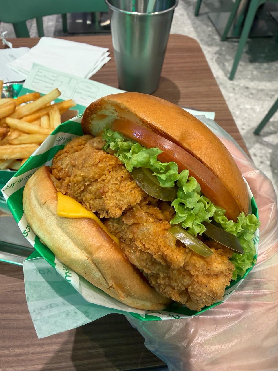 NakNak fried chicken burger with lettuce, tomato, pickles and fries on the side