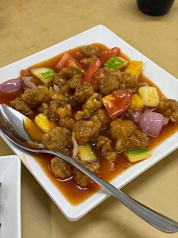 Meat and vegetables in brown sauce served on square plate